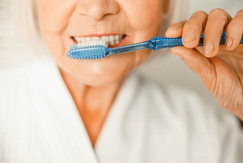 older woman brushing teeth