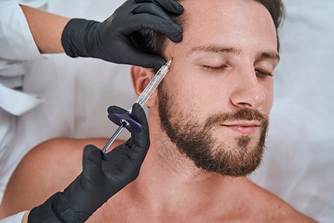 Man receiving filler injection near his temple