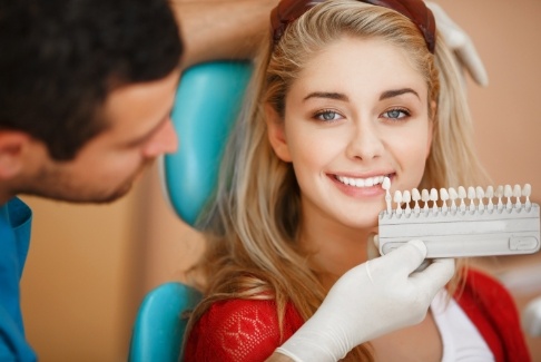 Woman's smile compared to porcelain veneers shade options at cosmetic dentistry appointment