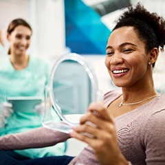 Female patient smiling while holding handheld mirror