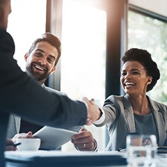 Woman smiling while shaking co-workers hand in conference room