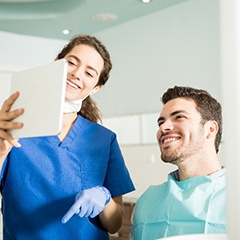 Dental assistant and patient smiling while reviewing information on tablet