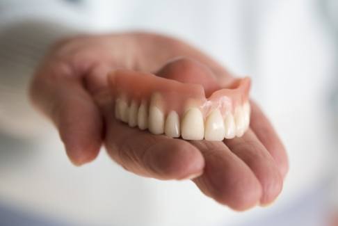 Hand holding a full denture