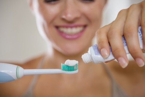 Woman brushing teeth to prevent dental emergencies