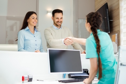 Man and woman at reception desk discussing the cost of dental emergencies