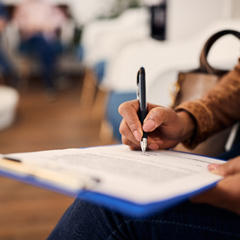 Woman’s hands filling out forms on blue clipboard