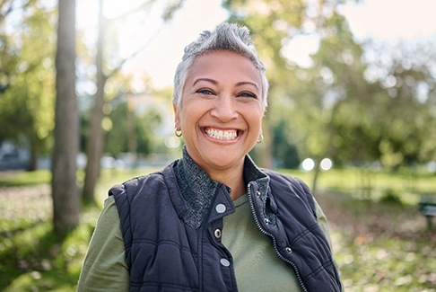 Senior woman with jacket standing outside and smiling