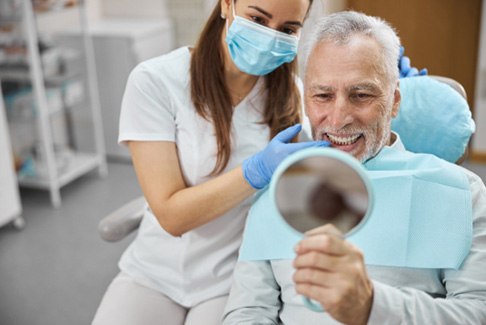 An older man admiring his new dental implant