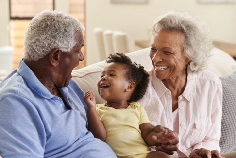 Laughing grand child with grandparents who are enjoying the benefits of dental implants