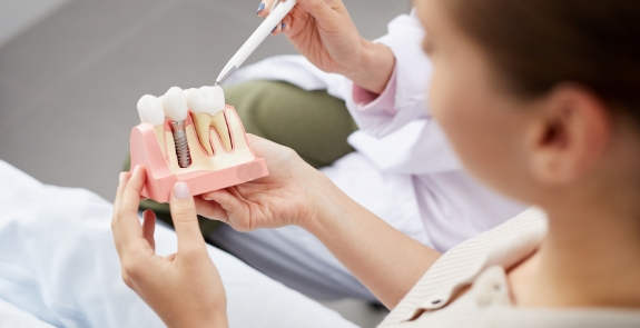 Dentist and patient looking at dental implant model