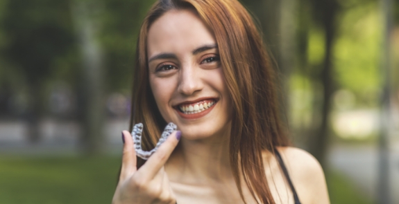 Smiling woman holding clear aligner tray