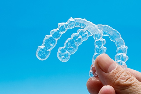 dentist holding two clear aligners 