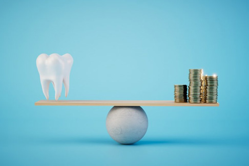 a tooth and coins balancing on a scale