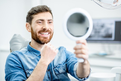 a patient checking his smile with a mirror