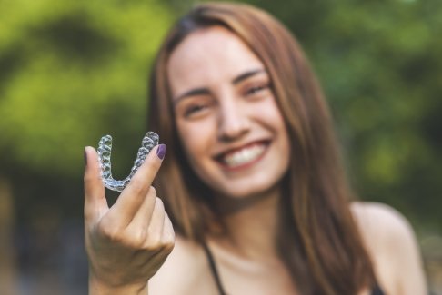 Woman holding up sure smile clear aligner