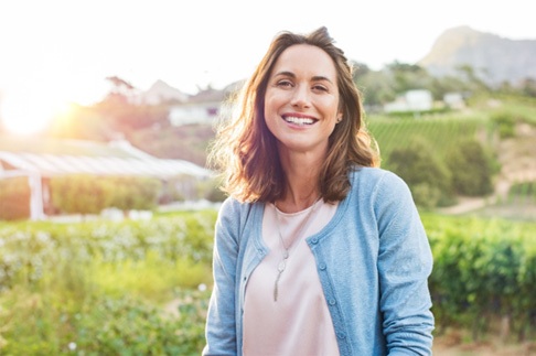 a woman smiling with veneers in a field