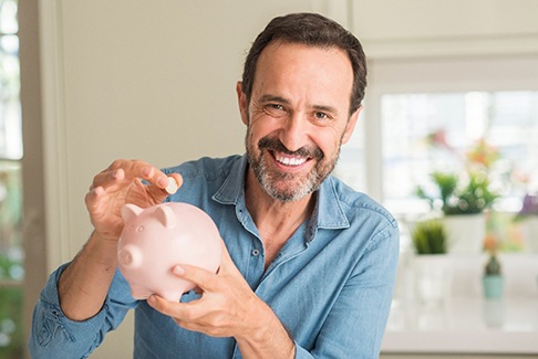 a man placing a coin in a piggy bank